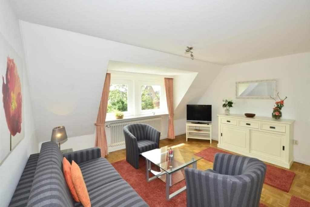 a living room with a couch and chairs and a television at Malvenhof, App OG in Wenningstedt
