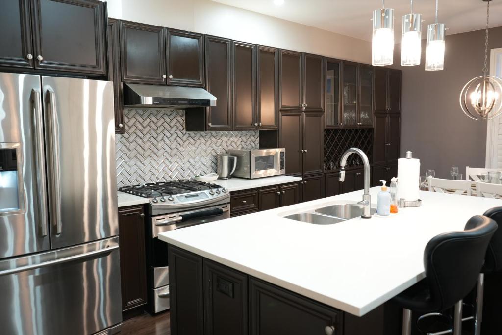 a kitchen with black cabinets and a stainless steel refrigerator at Luxury 5BR Home with Spa Bath in Burlington