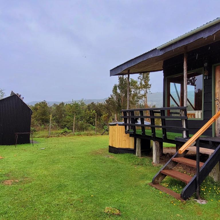 ein Gebäude mit Veranda und Rasenfläche in der Unterkunft Chiloe Profundo in Chonchi