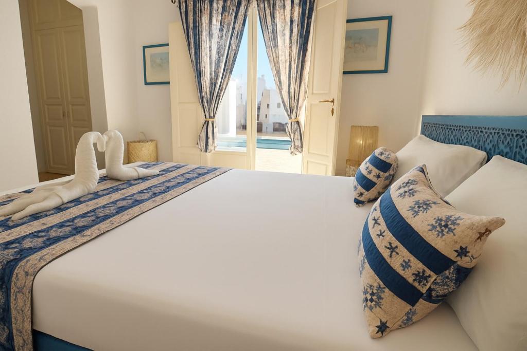 a bedroom with a large bed with blue and white pillows at Dar Néliah Djerba in Djerba