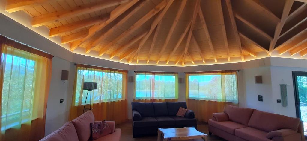 a living room with a wooden ceiling with windows at Cá du Mattu in Villa Pehuenia