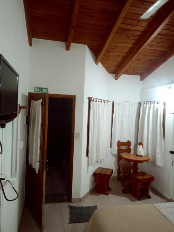 a room with a tv and a table and a door at Suites Piltri in El Bolsón