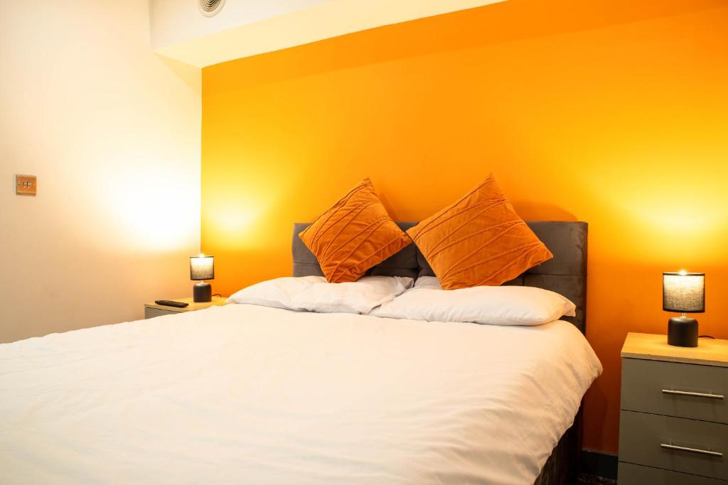 a bedroom with a bed with an orange wall at Studio Close To Alhambra And Bradford Live Walk To Stations in Bradford