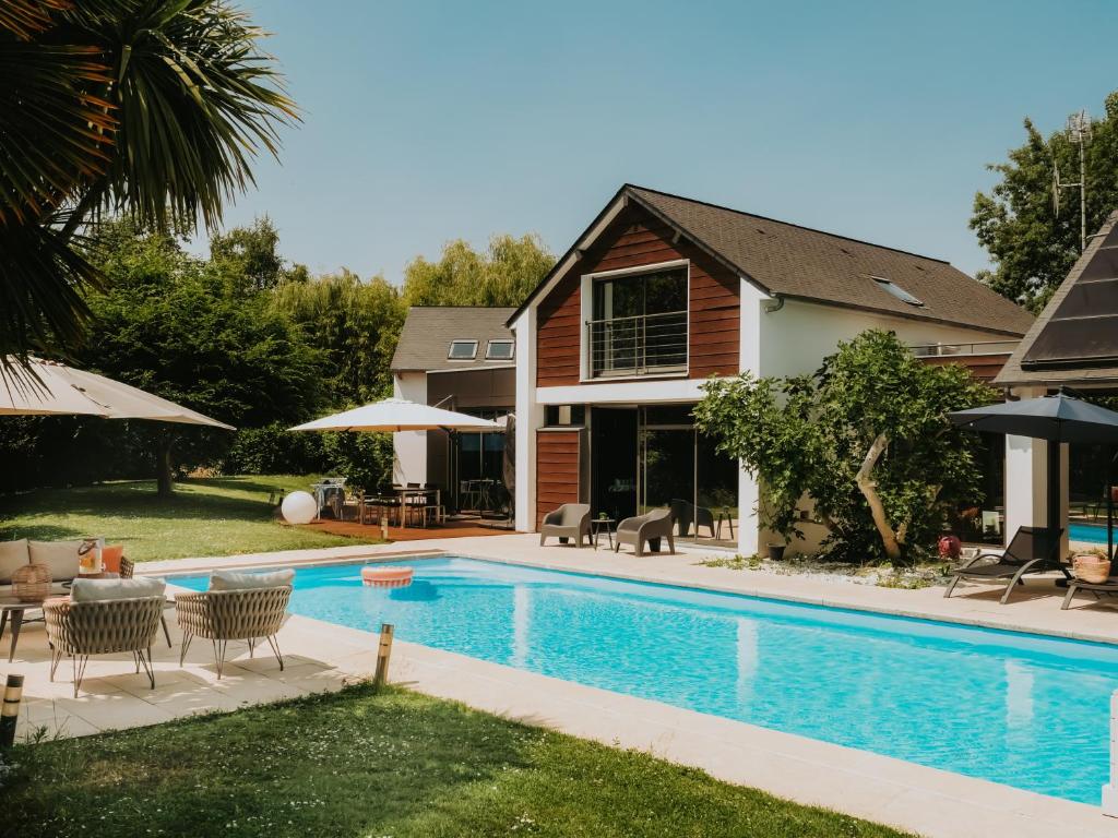 a swimming pool in front of a house at Les Arbres Rouges in Sucé