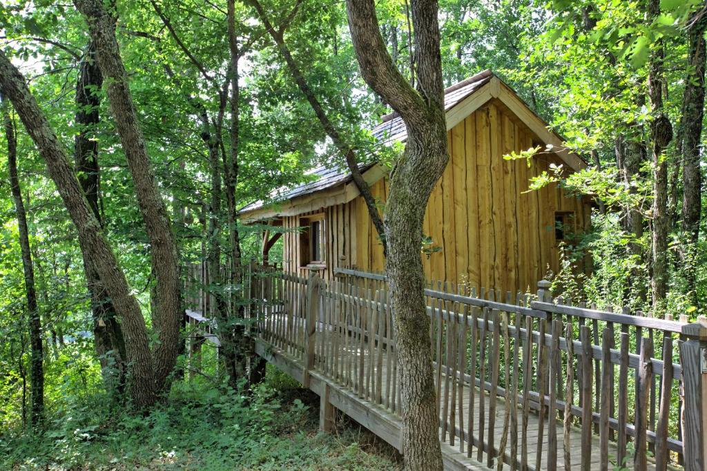 uma cabana de madeira na floresta ao lado de uma cerca em Les Cabanes des Benauges em Arbis