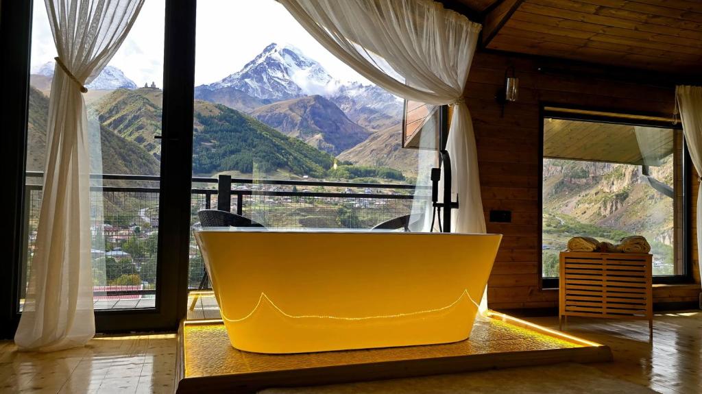 a yellow tub in a room with a view of a mountain at Rookhe Kazbegi in Kazbegi