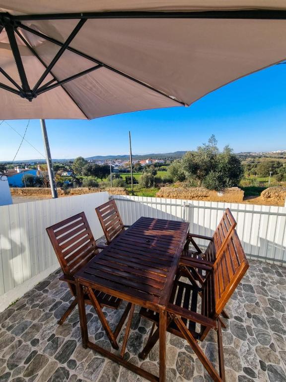 a table and chairs on a patio under an umbrella at Refúgio de Monsaraz in Monsaraz