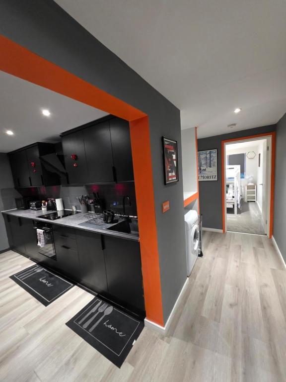 a kitchen with black cabinets and an orange stripe at Cozy Garden Apt - 8ight Havens in Folkestone