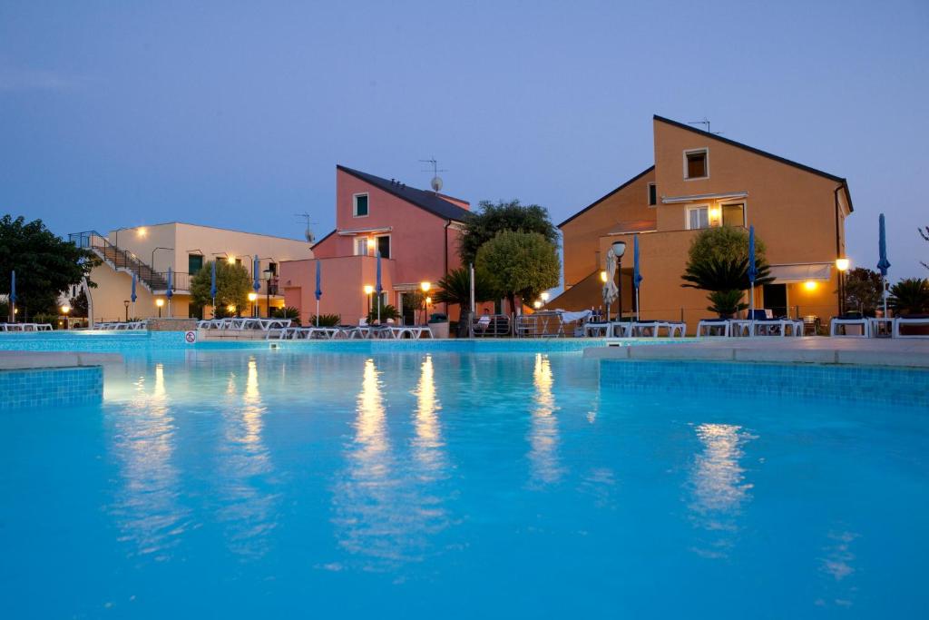a large swimming pool with blue water at night at Residence Borgomare in Albenga
