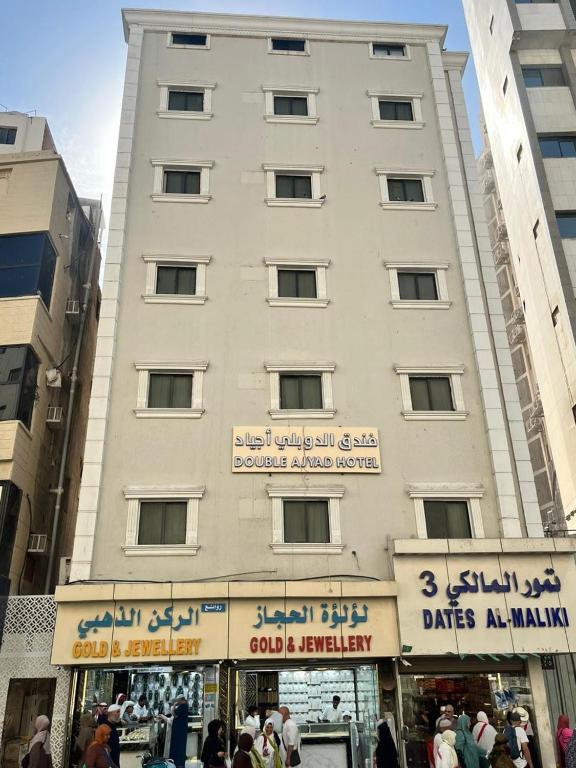 a tall white building with people standing in front of it at فندق الدوبلي أجياد in Quai