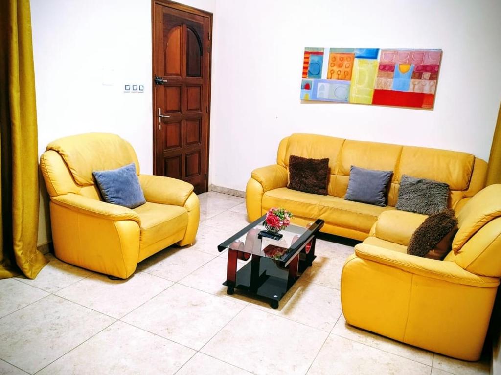 a living room with two yellow couches and a coffee table at Villa Julien 2 chambres in Rufisque