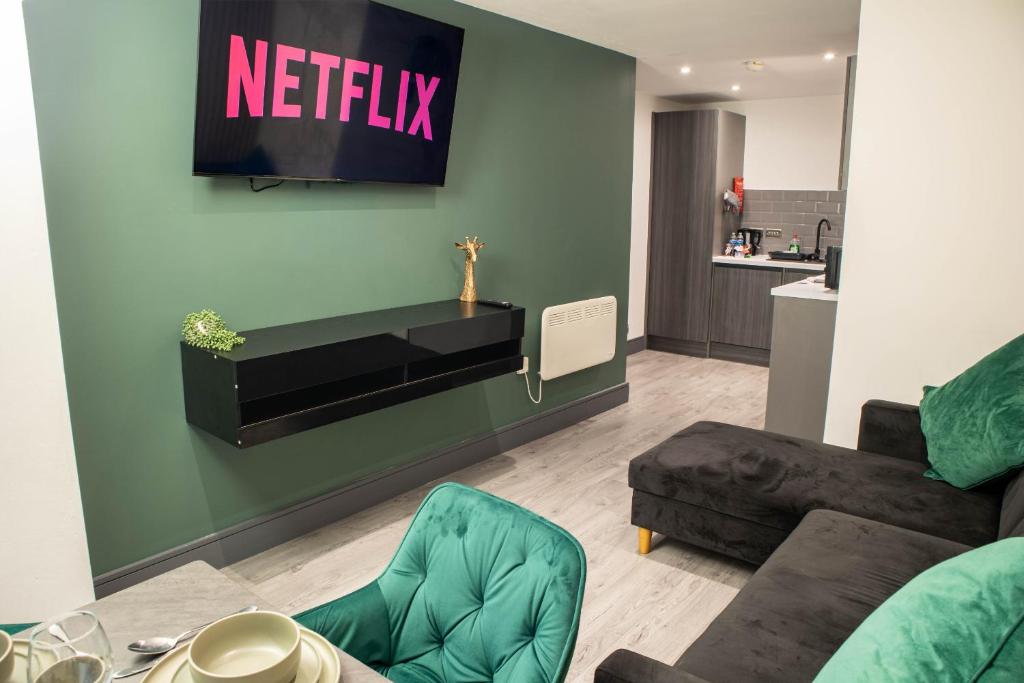 a living room with a couch and a tv on the wall at Luxury Serviced Apartment With Super King Bed Workspace WiFi & Netflix Washer Dryer Close Parking in Bradford
