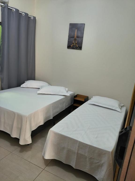 two beds sitting next to each other in a room at suíte para 3 pessoas com ar,tv e frigobar garagem para veículo de pequeno porte in Sinop