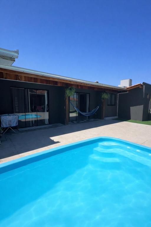 a blue swimming pool in front of a house at Apartamento 03 - Refúgio do Descanso in São Francisco do Sul