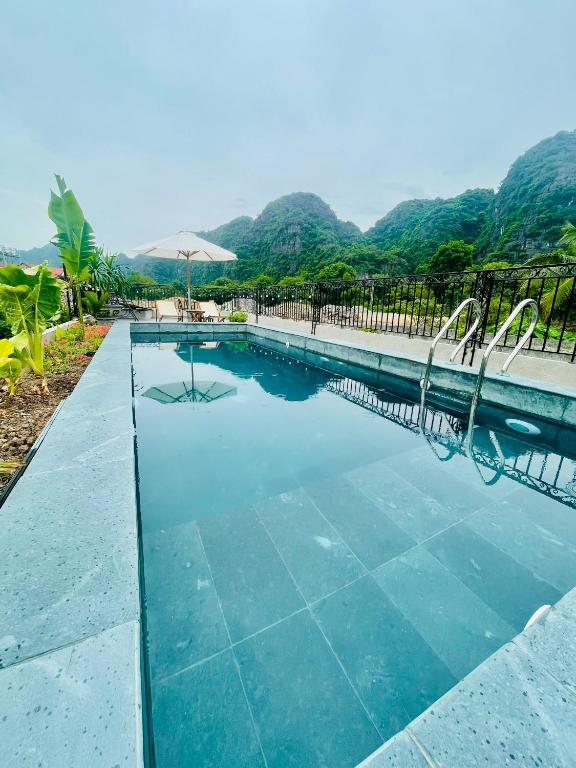 a swimming pool with mountains in the background at Tam Coc Hope House in Ninh Binh