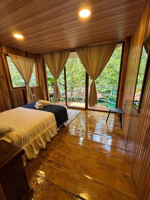 a bedroom with a bed in a room with windows at Mindo GlamBird Glamping & Lodge in Mindo