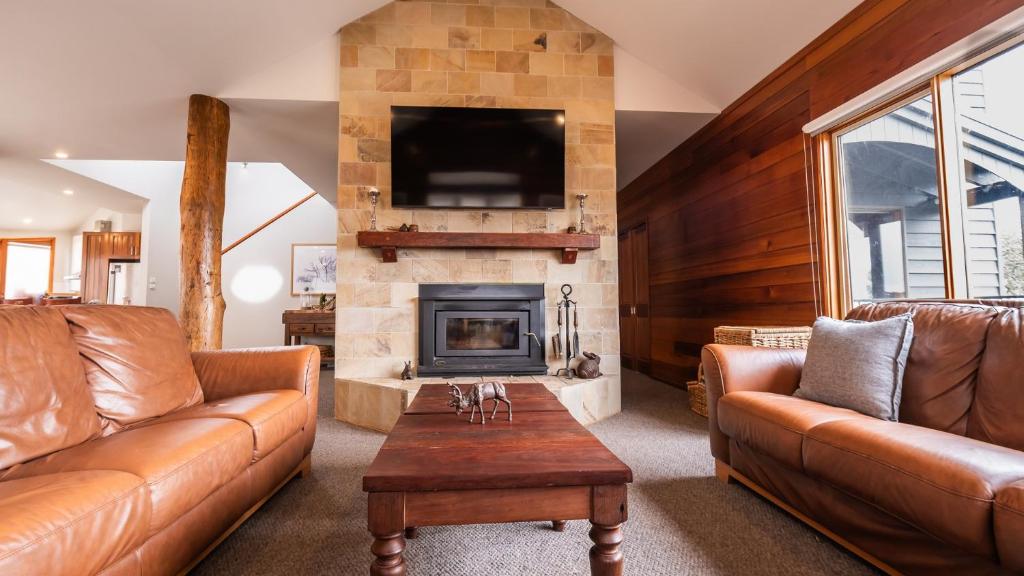a living room with leather furniture and a fireplace at Camelot in Dinner Plain