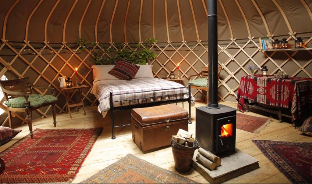 a room with a bed and a stove in a yurt at JOY Retreat in Isle of Jersey