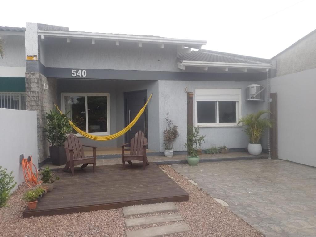 a patio with two chairs and a hammock outside of a house at Casa aconchegante e completa em Osório - Ótima localização in Osório