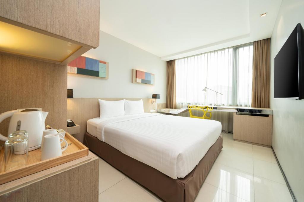 A bright double room with a glossy tiled floor and window-side storage.