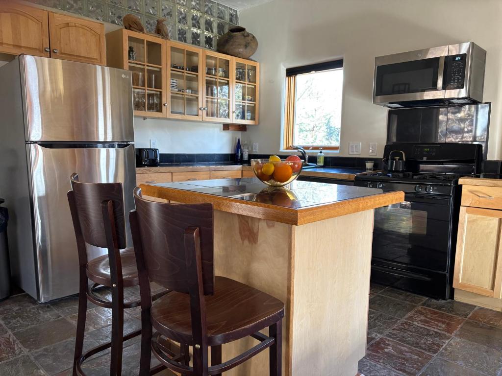 a kitchen with a refrigerator and a counter with a bowl of fruit on it at High Moon 4 Ten Thousand Waves Way in Santa Fe