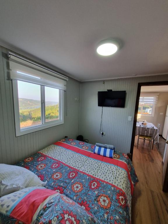 a bedroom with a bed and a window and a television at Cabaña 2 a 4 personas in Carahuo