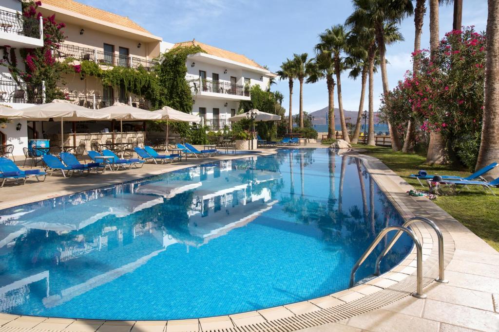 una gran piscina con sillas azules y palmeras en Almyrida Resort, en Almyrida