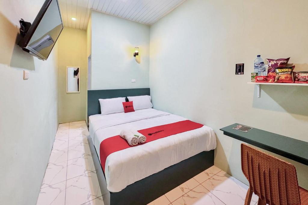a small room with a bed with a red blanket at RedDoorz at Ingan Cio Homestay Berastagi in Berastagi