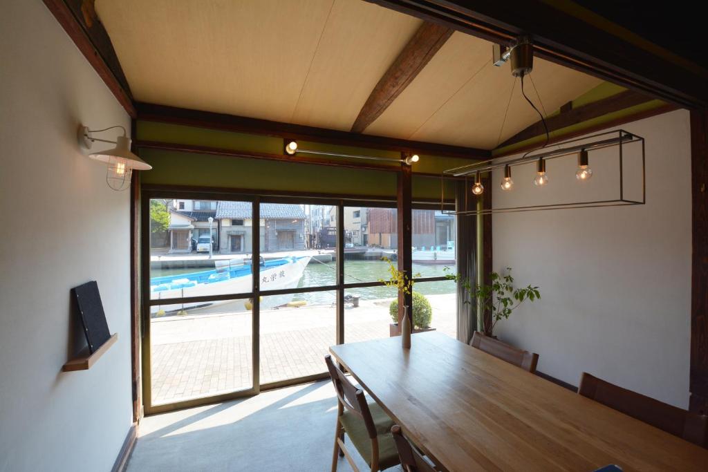 a dining room with a wooden table and a large window at MINKA Riverside Villas in Shimminato