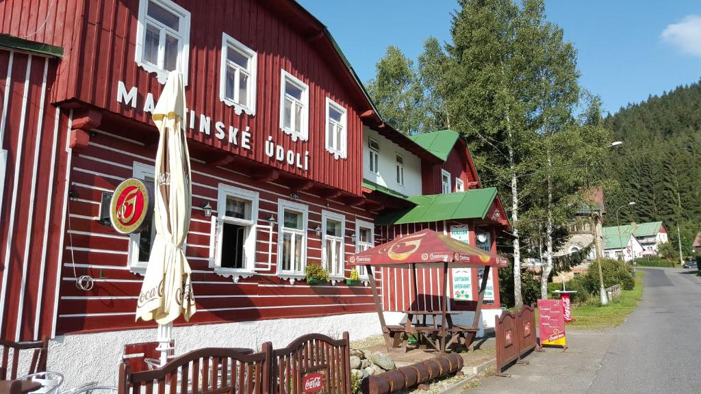 een rood gebouw met een bord aan de zijkant bij Pension Martinské údolí in Kořenov