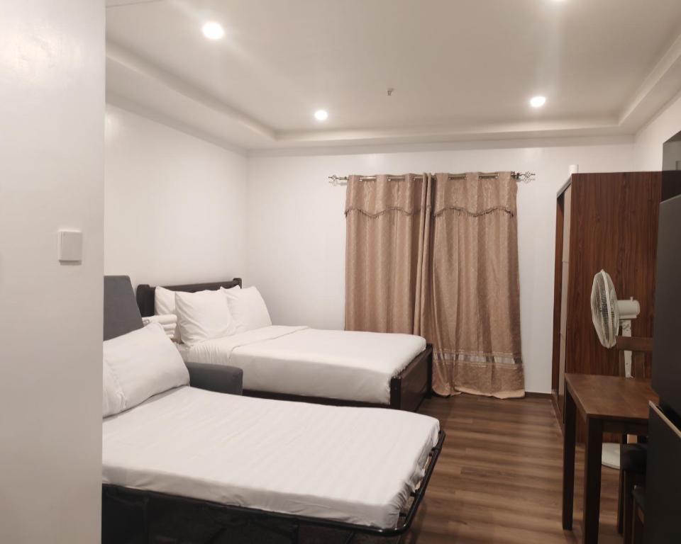 a hotel room with two beds and a desk at Raya's Staycation Megatower 7 Baguio City in Baguio