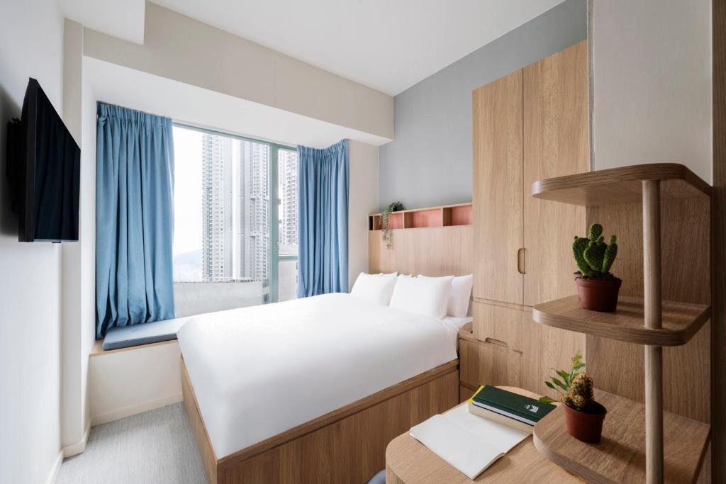 a hotel room with a bed and a window at Weave Studios - Olympic in Hong Kong