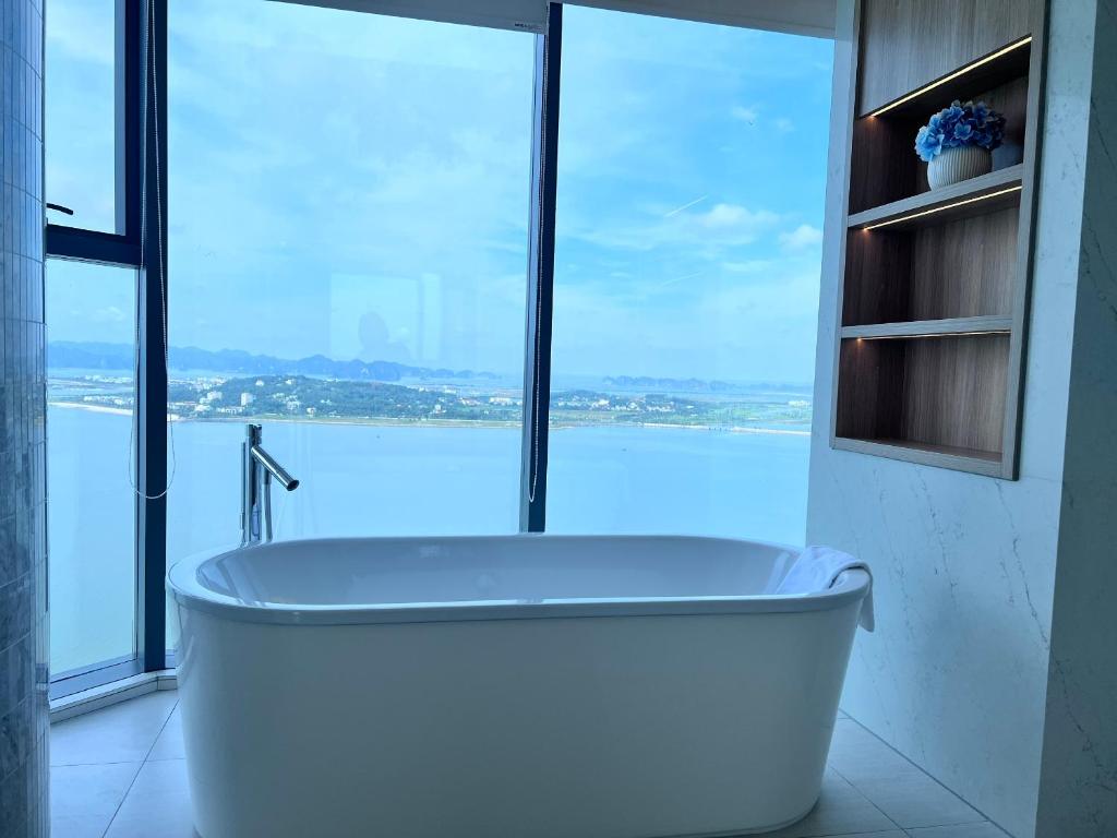 a bath tub in a bathroom with a large window at Executive Bay View A La Carte Hạ Long in Ha Long