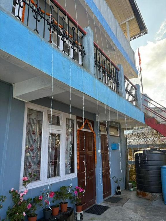 a blue building with potted plants and a balcony at Bluemoon stay in Darjeeling