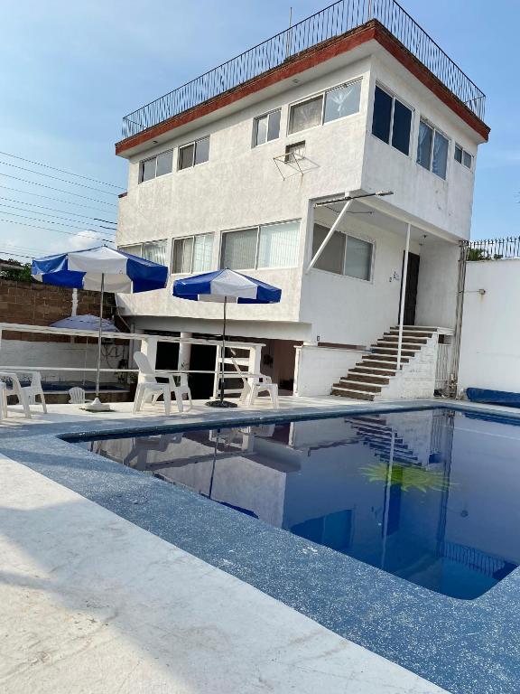a house with a swimming pool with umbrellas and chairs at Casa El nido de las flores in Oaxtepec