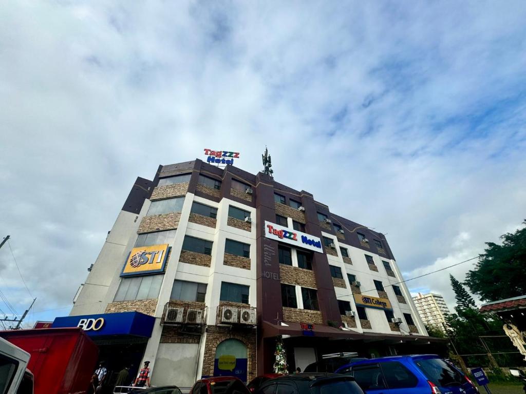a tall building with cars parked in front of it at Tagzzz Hotel powered by Cocotel in Tagaytay