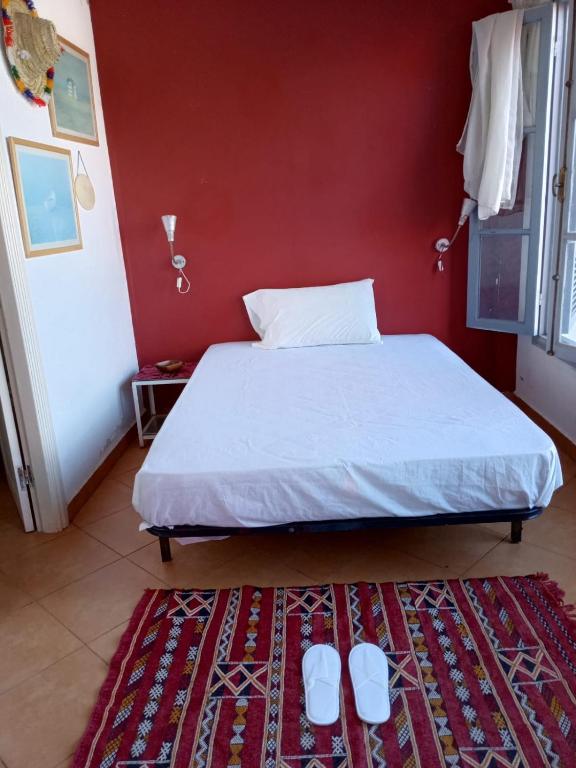 a bedroom with a bed and a red wall at Maison Sevilla in Larache