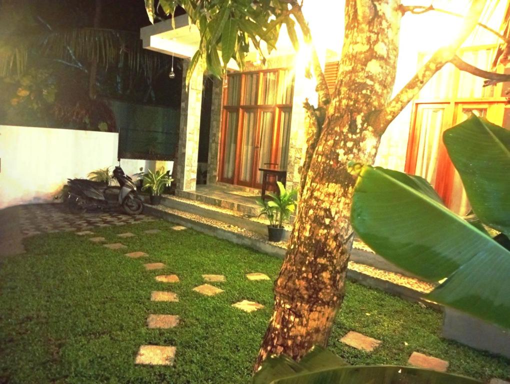 a house with a tree and a motorcycle in the yard at Aureva Guest in Weligama
