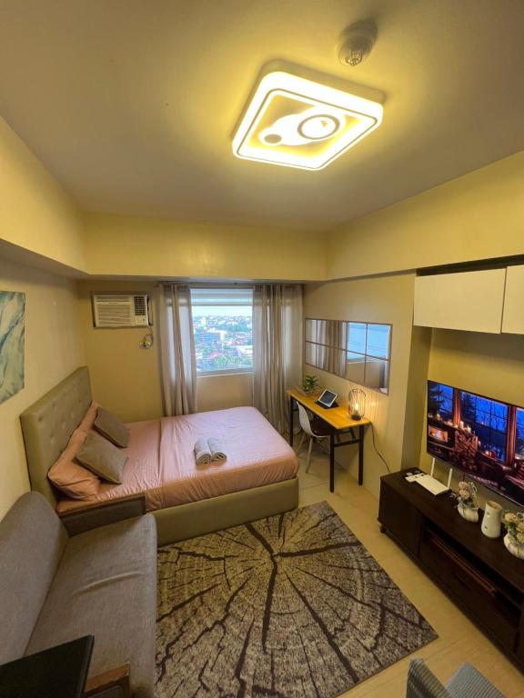 a bedroom with a bed and a couch and a television at Avida Tower 2 in Davao City