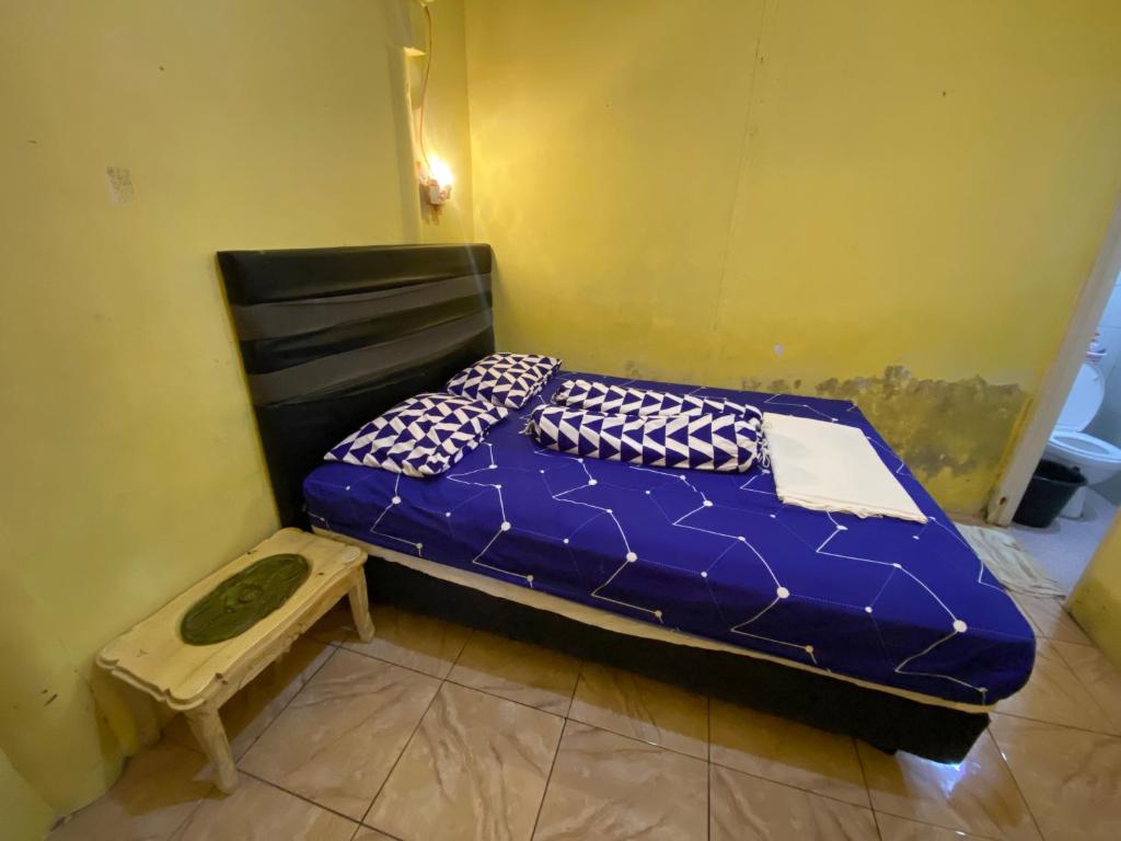 a blue bed in a room with a stool at Hatiku Guesthouse in Bunaken