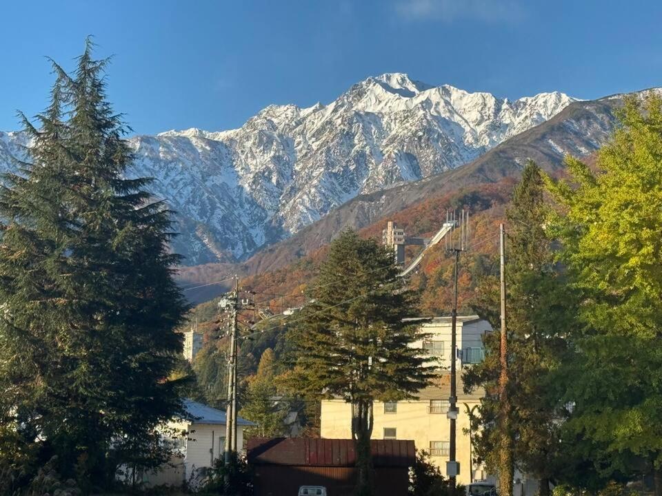 a view of a mountain range with trees and buildings at 2 Peaks Snow Lodge in Hakuba