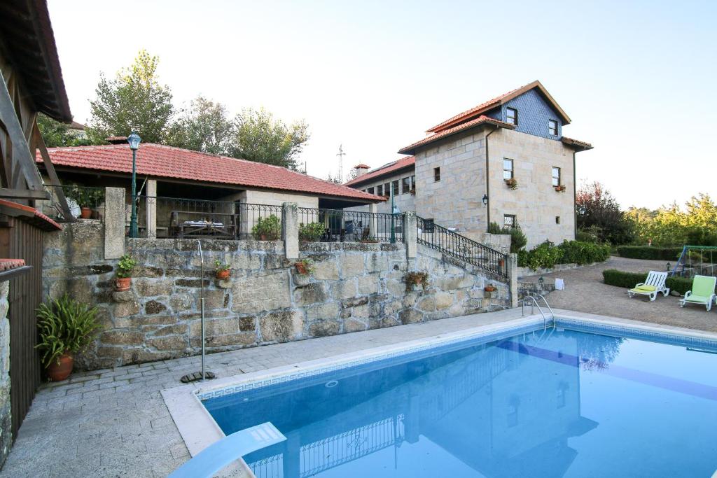 a swimming pool in front of a house with a building at Casa Rural Da Costeira in Cinfães