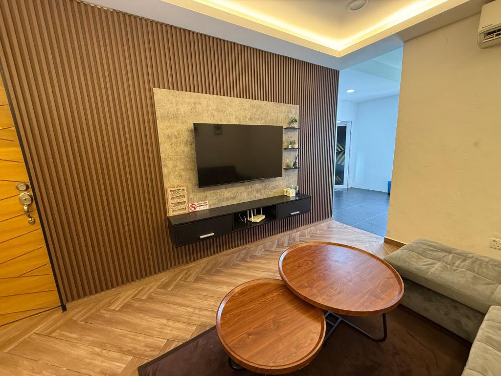 a living room with two wooden tables and a tv at Ujang Guest House in Batu Kikir