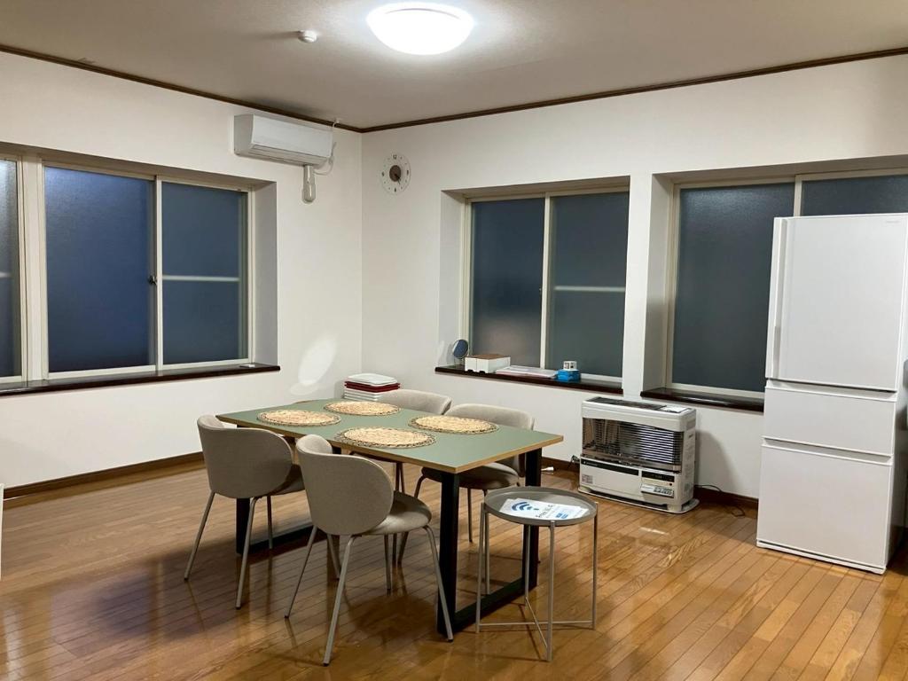 a kitchen with a table and chairs and a refrigerator at mahoratto inn in Aomori