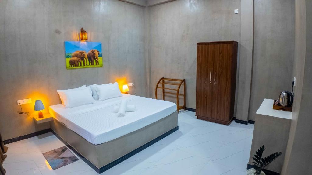 a bedroom with a large white bed and a wooden cabinet at Dana Villa in Bentota