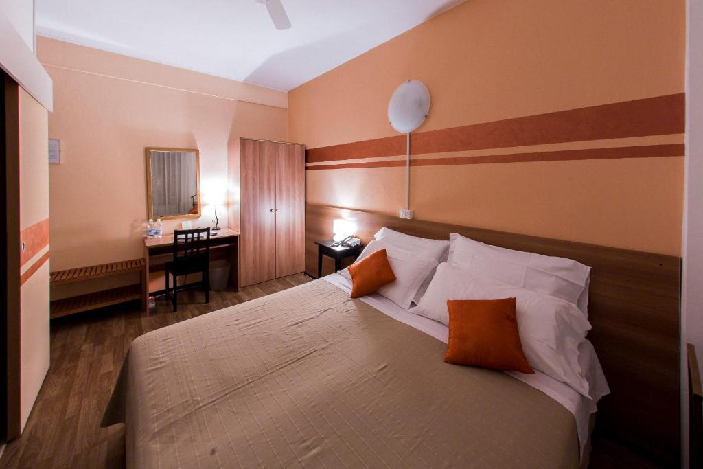 um quarto com uma cama com almofadas laranja e uma secretária em Quari Hotel Restaurant & Pizza em Cologna Veneta