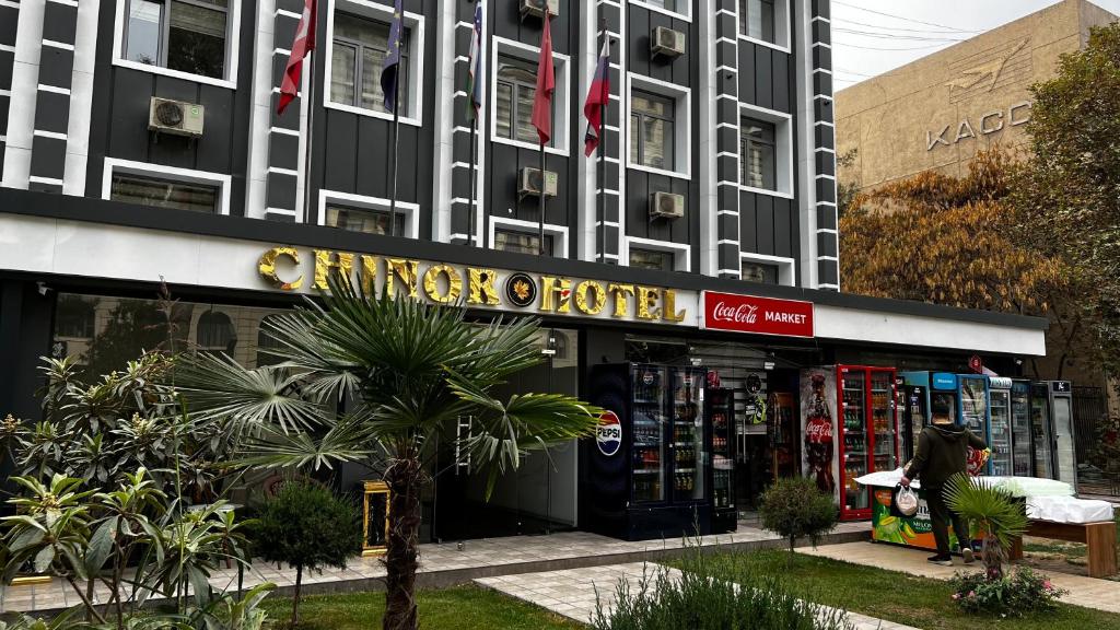 a woman standing in front of a building at Chinor Hotel Fergana in Fergana