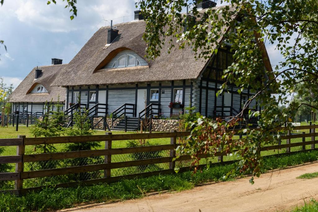 an old black house with a wooden fence at Szelągówka Camping&Apartments in Sorkwity