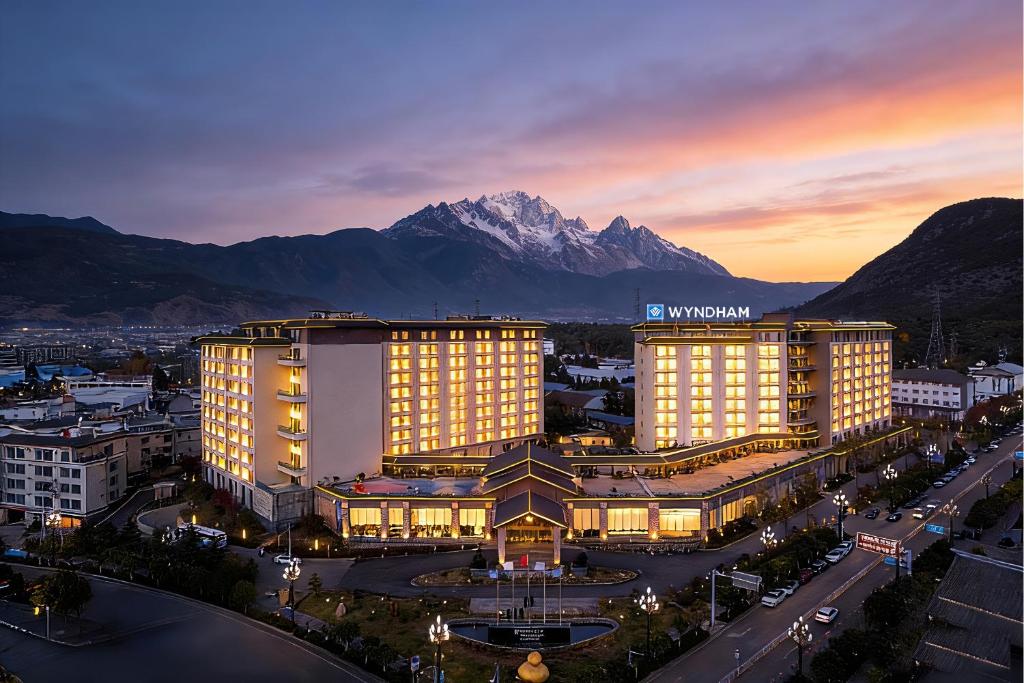 a large building with a mountain in the background at Wyndham Lijiang Yulong in Lijiang