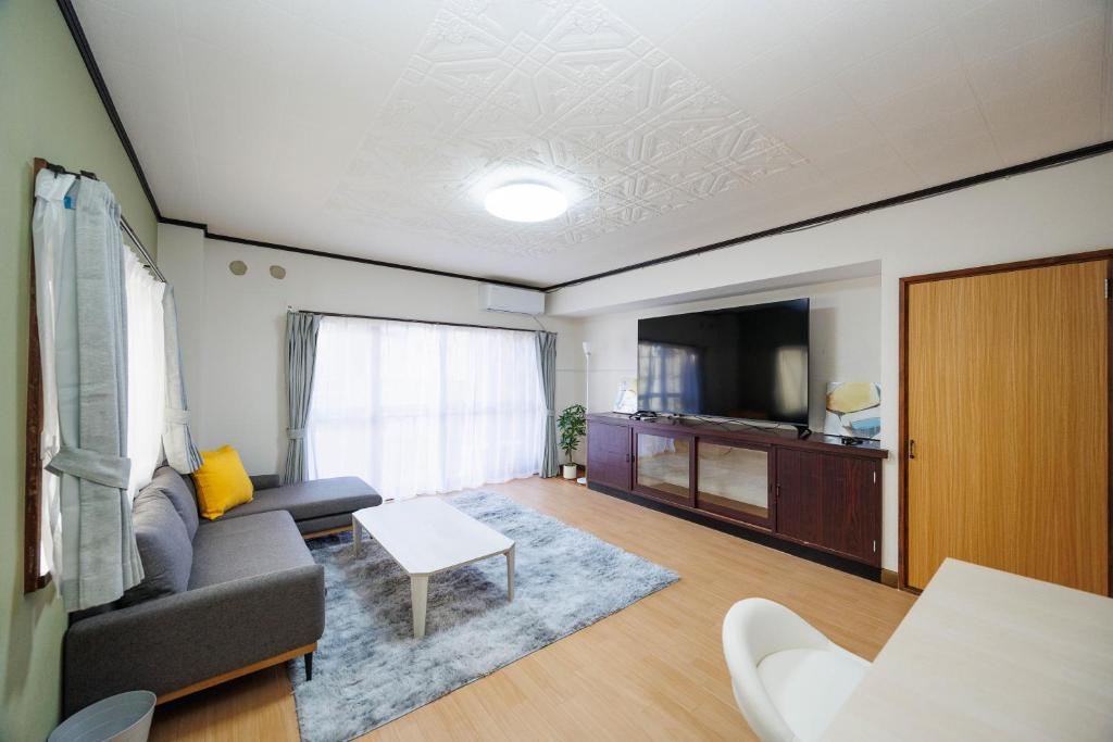 a living room with a couch and a tv at WAKE Inn 府中 in Fuchu